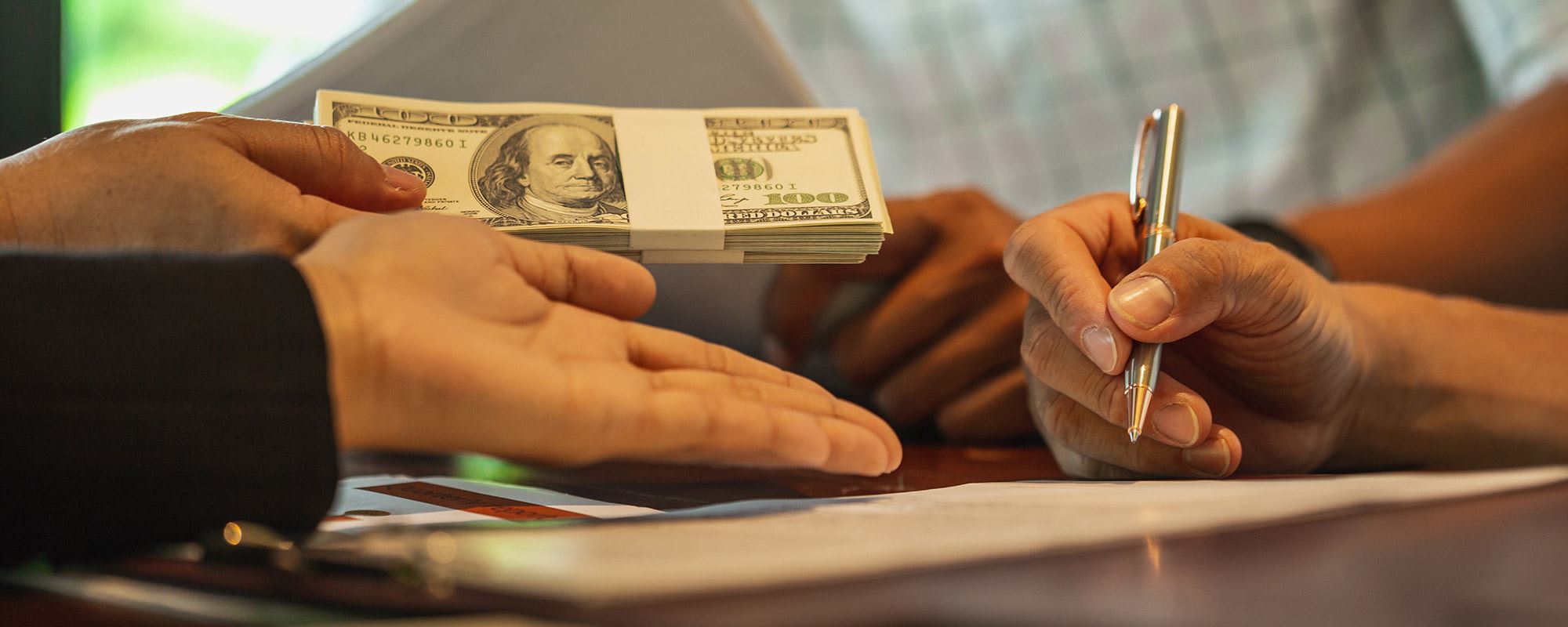 Hands signing paperwork and exchanging money